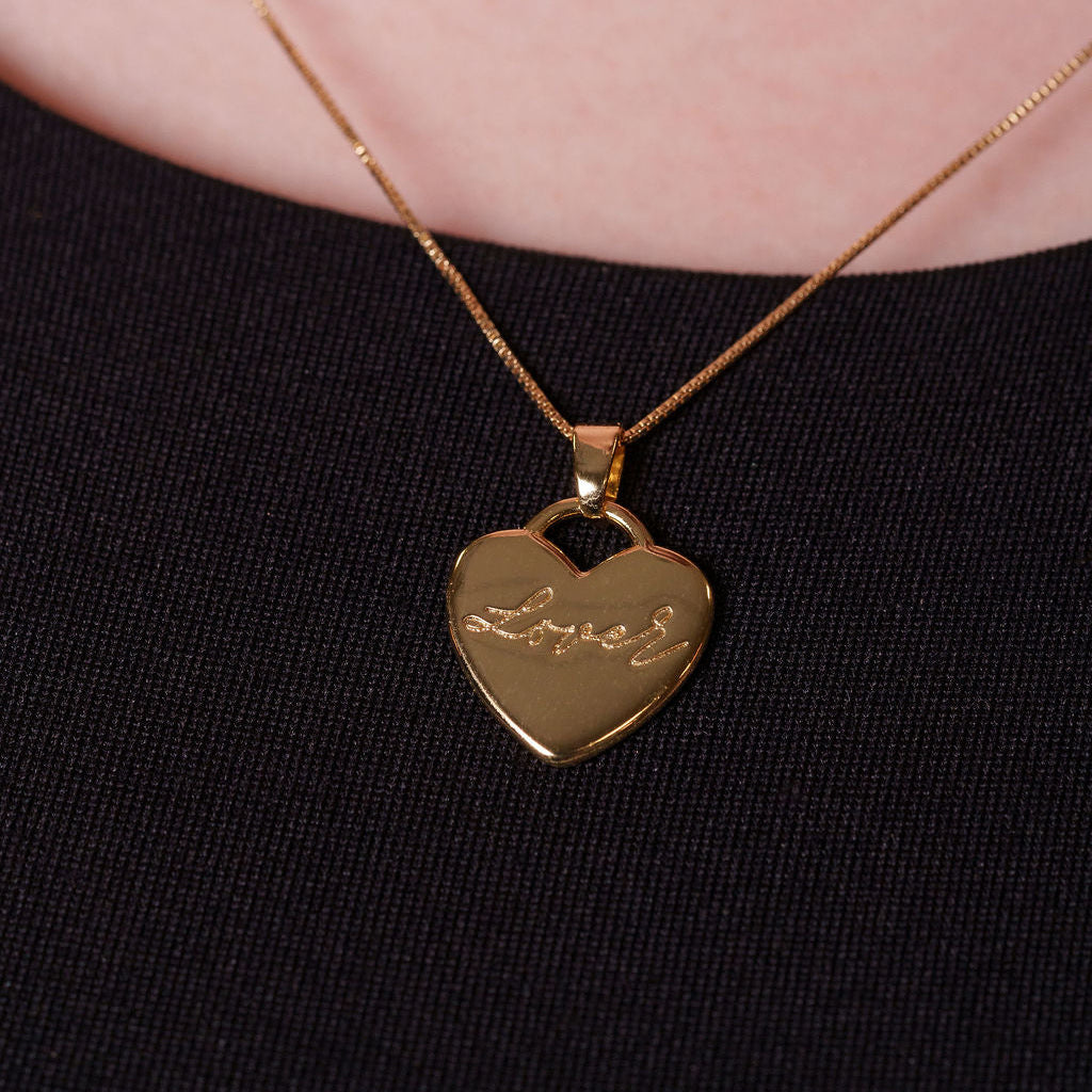 Gold heart-shaped pendant necklace on a black background