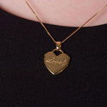 Gold heart-shaped pendant necklace on a black background