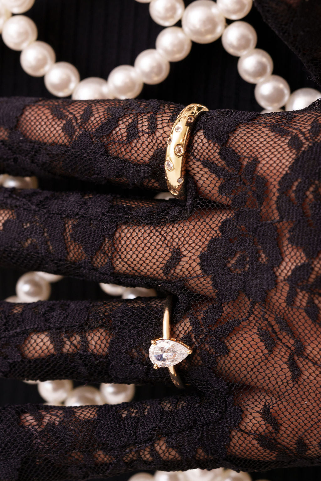 Glitz Ring and Adeline pear-cut ring in gold, worn over black lace gloves with pearls