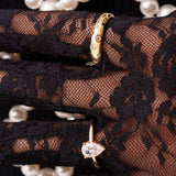 Glitz Ring and Adeline pear-cut ring in gold, worn over black lace gloves with pearls